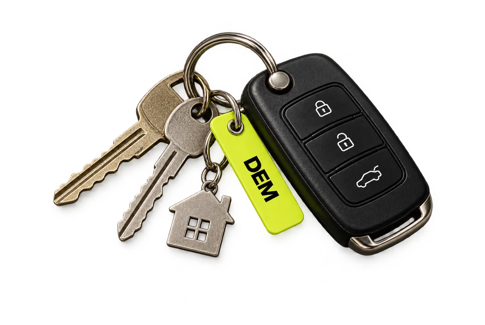 A set of house and car keys on a ring with a lime DEM tag.